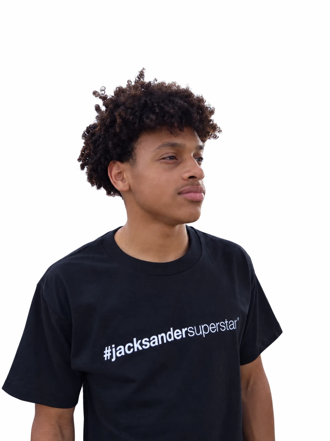 Curly-haired model in a black jacksandersuperstar tee, looking to the right.